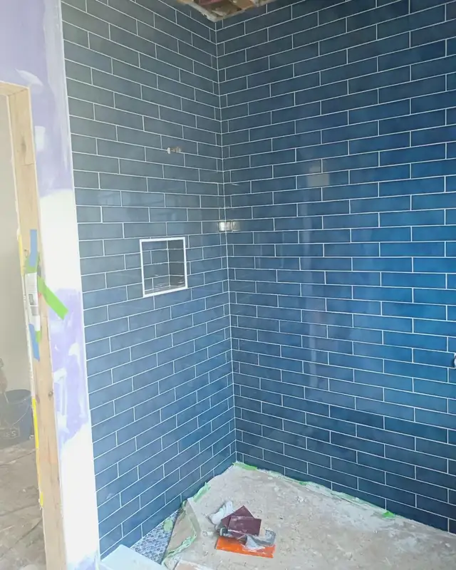 Blue glossy subway tile shower wall with recessed niche