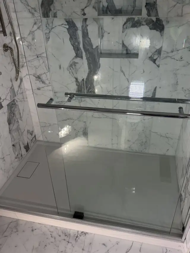 White marble-look porcelain shower with a sliding glass door