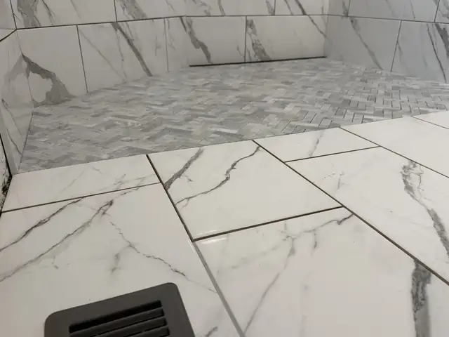 Large marble-look porcelain bathroom floor leading to a shower with a hexagon mosaic floor